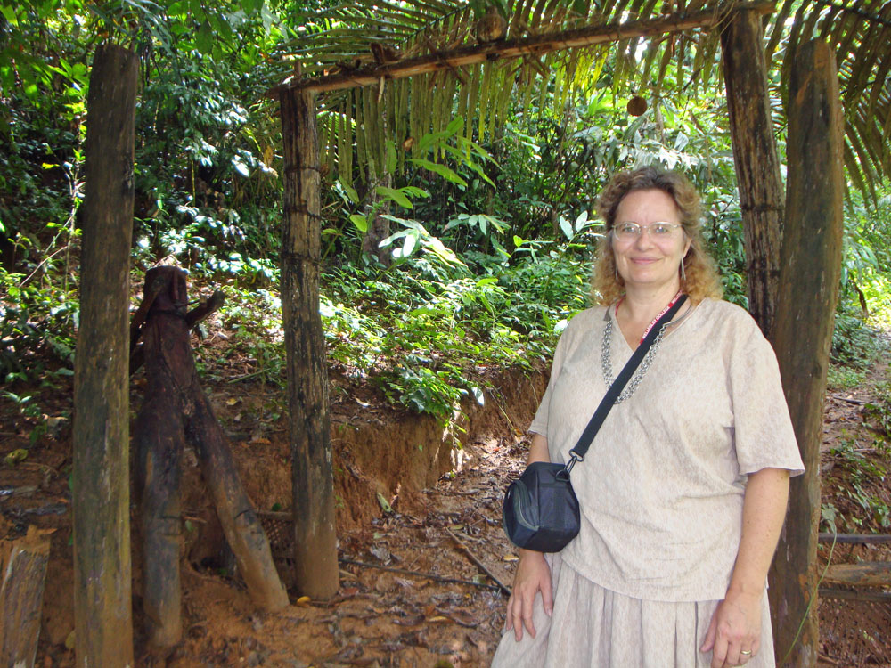 Maren in front of an Akha Spirit Gate with a human figure showing the people’s side of the gate, NW Laos.