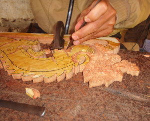 He carefully carves the dragon-shaped wooden hanger with hand tools.
