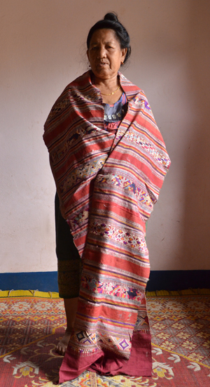 A Ban Tao elder poses with her silk coffin cover she wove when she was 17 years old.