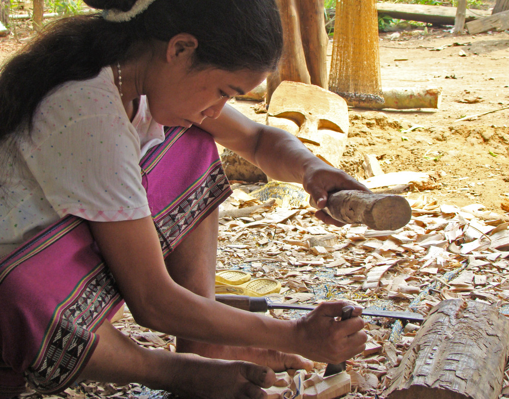 A Ta-Oy woman carving a protective mask in her village in Laos.