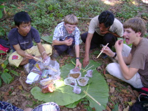 Tui, Zall, Tui’s friend, and Ari eating lunch by the side of the trail on a tablecloth of banana leaves.